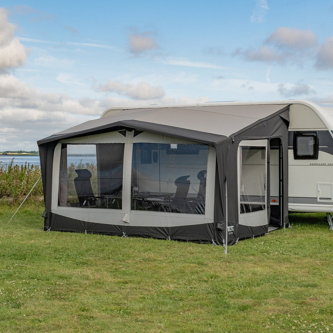 Caravan with an attached awning on a grassy area with a lake and sky in the background